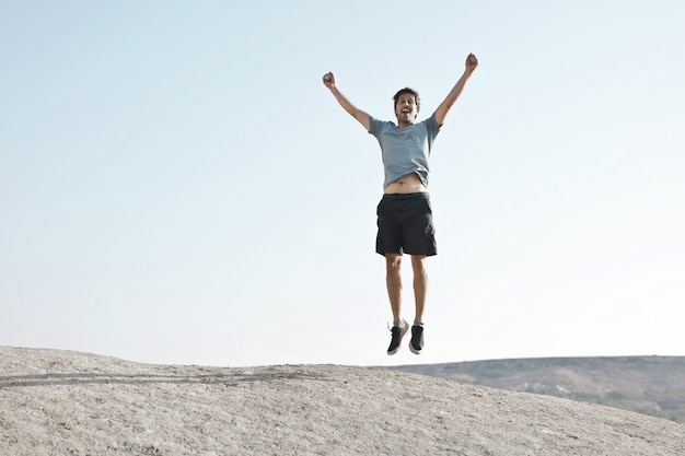 Hombre saltando con los brazos hacia arriba que representan la libertad o el éxito