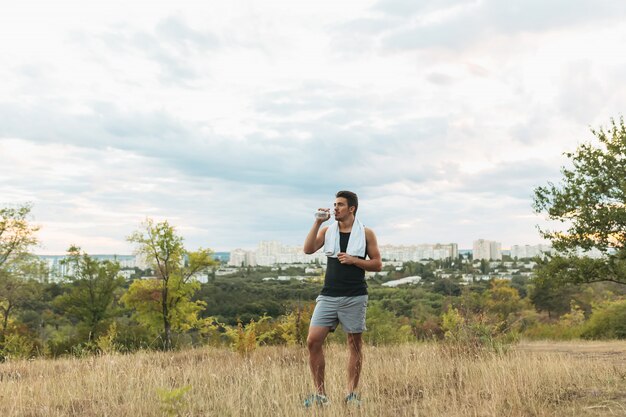 Hombre sano agua potable en la naturaleza mientras descansa