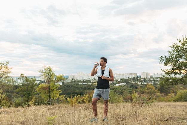 Hombre sano agua potable en la naturaleza mientras descansa