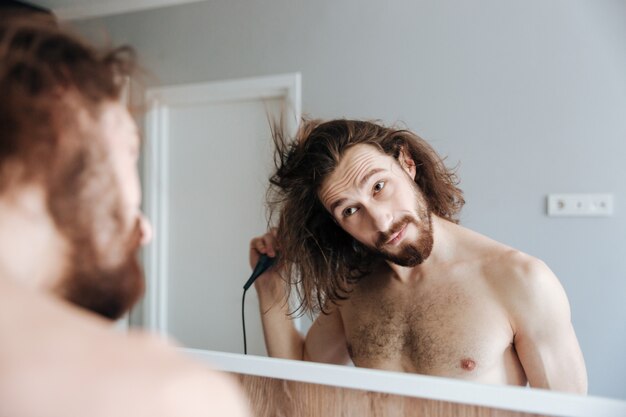 Hombre secando el cabello con secador de pelo en casa