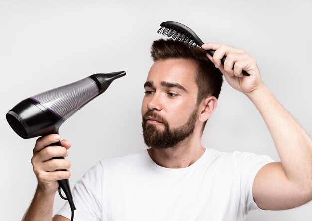 Hombre secándose el cabello y cepillándolo