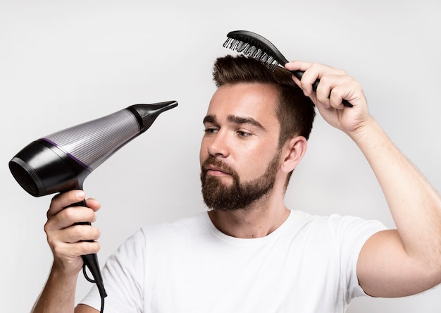 Hombre secándose el cabello y cepillándolo