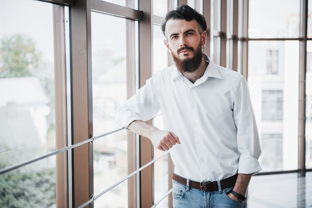 Un hombre seductor con una camisa blanca mirando a la cámara.