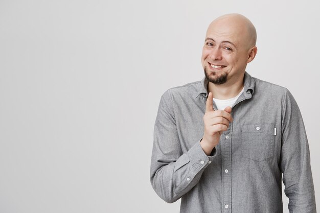 Foto gratuita hombre señalando con el dedo y sonriendo complacido, bien jugado