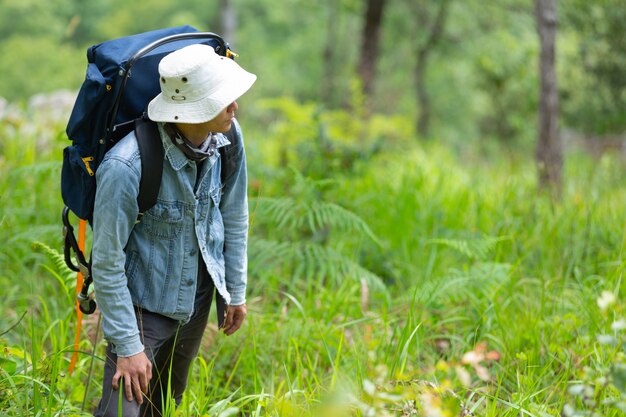 Un hombre de senderismo feliz camina por el bosque con una mochila.