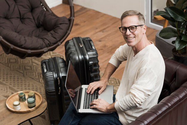 Hombre senior de alto ángulo mirando a través de su computadora portátil