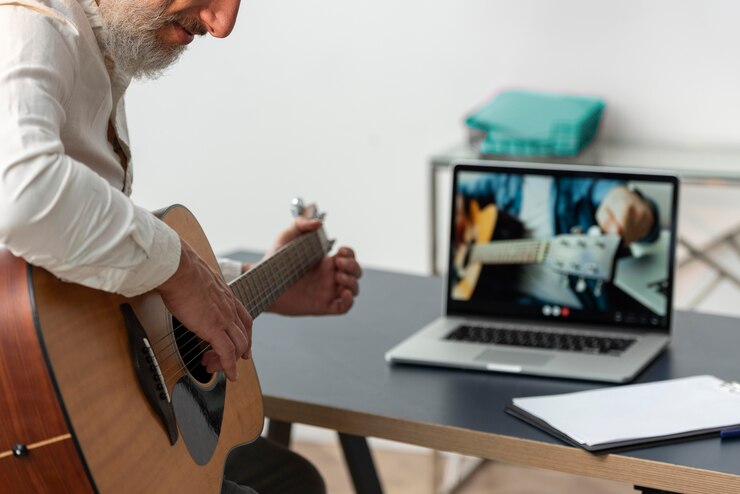 Foto gratuito hombre senior en casa estudiando lecciones de guitarra en portátil