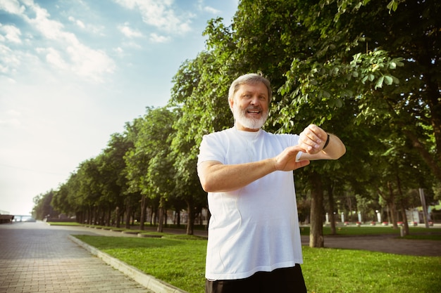 Hombre senior como corredor con rastreador de fitness en las calles de la ciudad