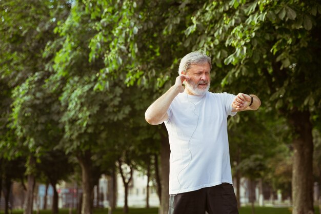 Hombre senior como corredor con rastreador de fitness en las calles de la ciudad