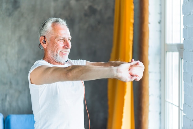 Hombre senior feliz estirando su mano mientras hace ejercicio