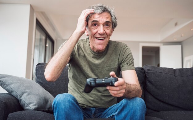 Hombre senior feliz jugando videojuegos en casa