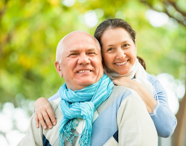 Hombre senior feliz y mujer madura contra el bosque