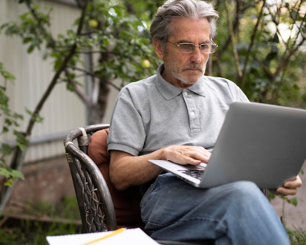 Foto gratuita hombre senior haciendo clases en línea en un portátil.