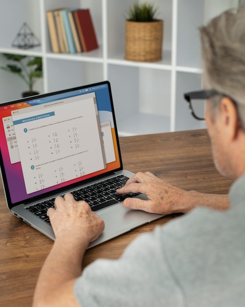 Hombre senior haciendo clases en línea en un portátil.