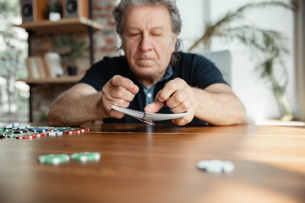 Hombre senior jugando a las cartas y bebiendo vino con amigos