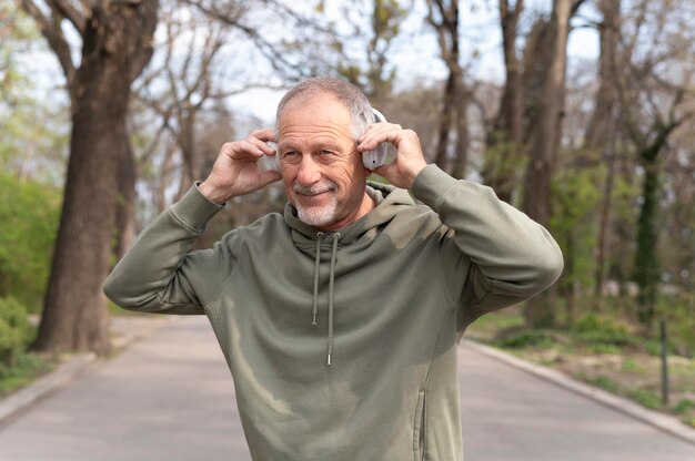 Hombre senior moderno escuchando música en un auricular