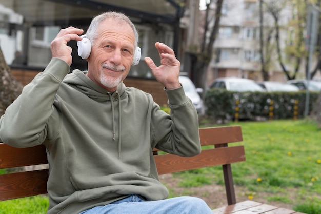 Hombre senior moderno escuchando música en un auricular