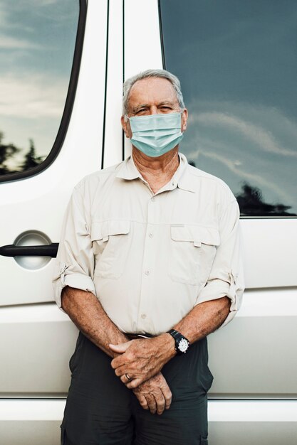 Hombre senior de pie junto a la autocaravana en la nueva normalidad