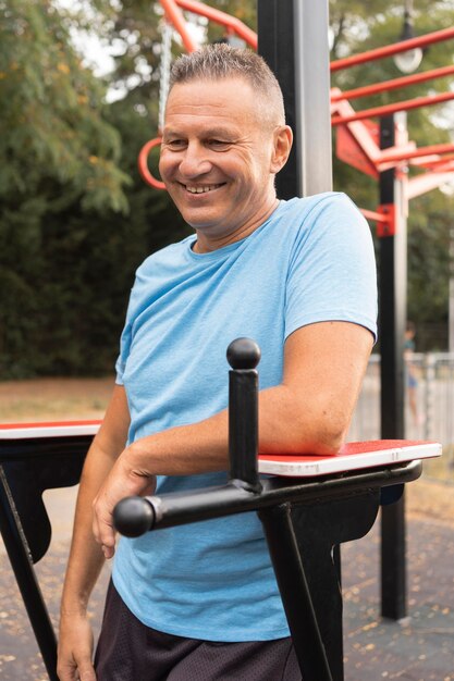 Hombre senior sonriente posando mientras hace ejercicio al aire libre