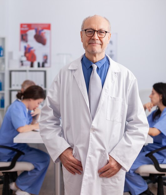 Hombre senior de terapeuta de pie delante de la cámara analizando los síntomas de la cirugía