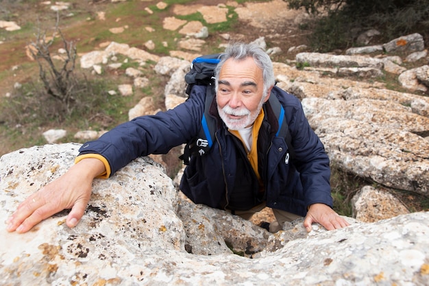 Hombre senior de tiro completo escalando roca