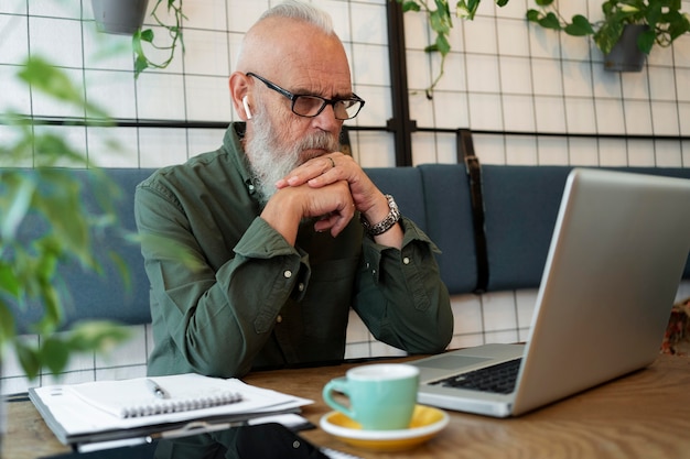 Hombre senior de tiro medio estudiando con portátil