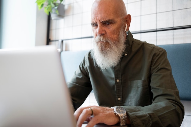 Hombre senior de tiro medio estudiando con portátil