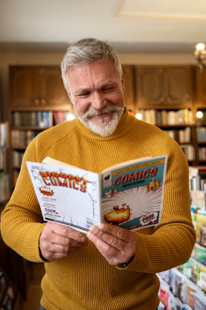 Foto gratuita hombre senior de tiro medio leyendo cómics