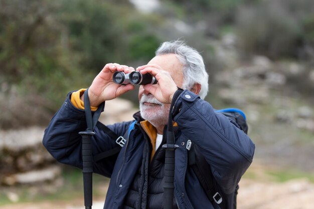 Hombre senior de tiro medio usando binoculares