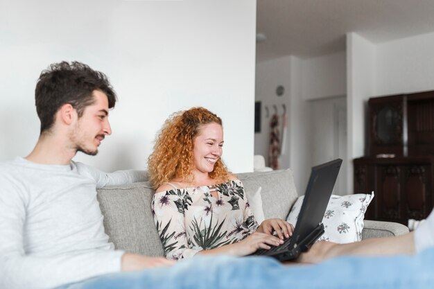 Hombre sentado además de mujer feliz usando laptop