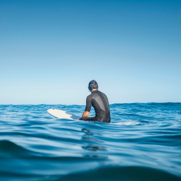 Hombre sentado en el agua desde atrás