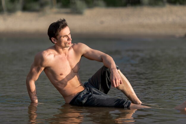 Hombre sentado en el agua en la playa
