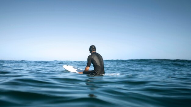 Hombre sentado en el agua desde el tiro trasero