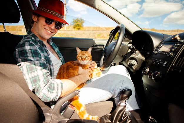 Hombre sentado en el asiento del conductor con un gato