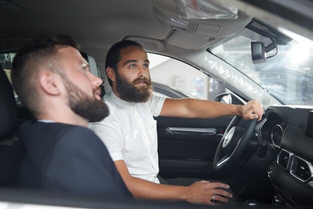 Hombre sentado en el asiento del conductor probando el auto con el gerente