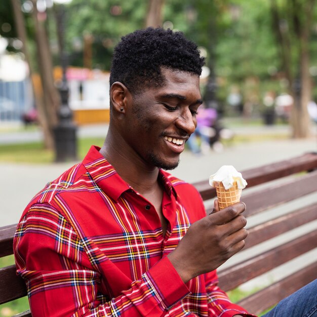 Hombre sentado en un banco y comiendo helado