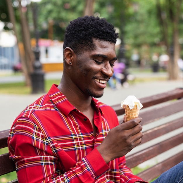 Hombre sentado en un banco y comiendo helado