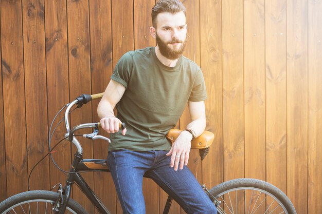 Hombre sentado en bicicleta contra el fondo de madera