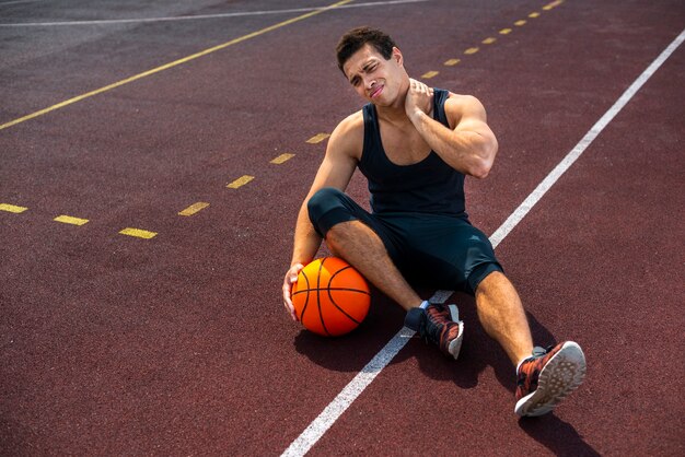 Hombre sentado en la cancha de baloncesto