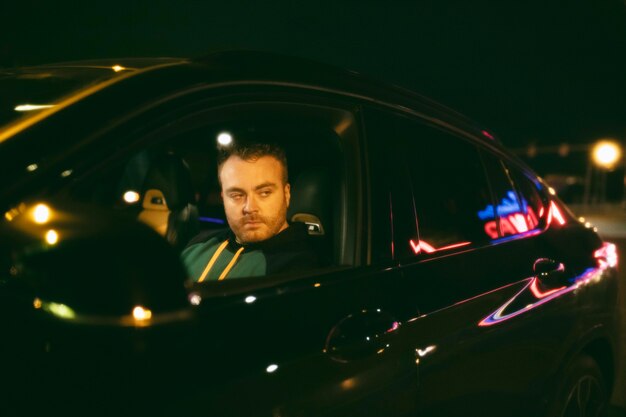 Hombre sentado en el coche por la noche