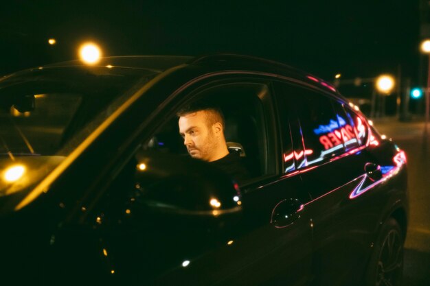 Hombre sentado en el coche por la noche