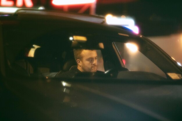 Hombre sentado en el coche por la noche