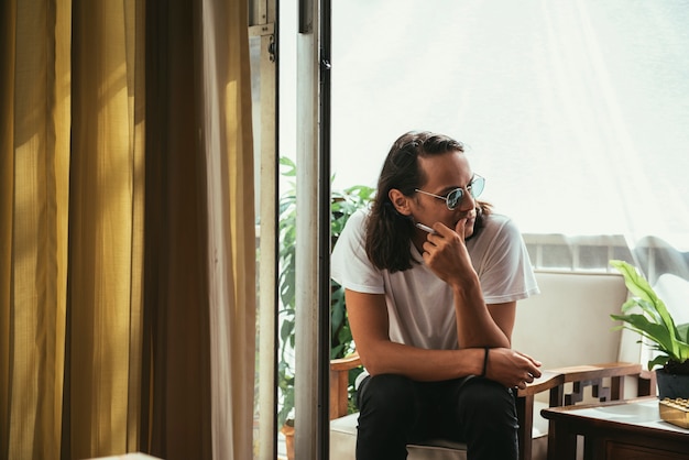 Foto gratuita hombre sentado y fumando en un balcón