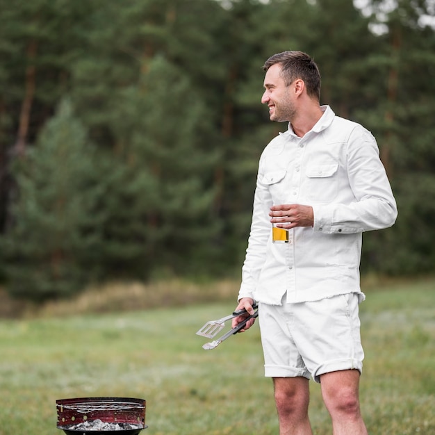 Foto gratuita hombre sentado junto a la barbacoa y tomar una cerveza