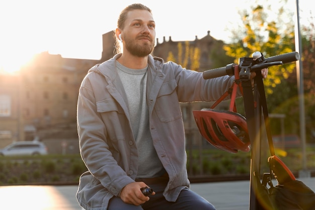 Foto gratuita hombre sentado junto a su scooter