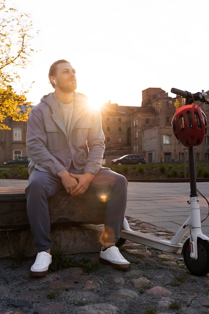 Foto gratuita hombre sentado junto a su scooter