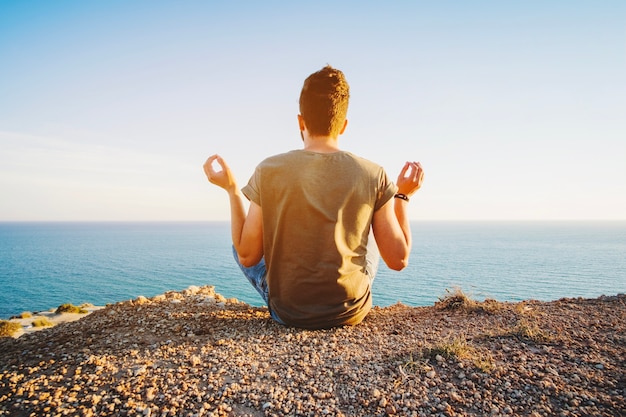 hombre sentado y meditando en el océano