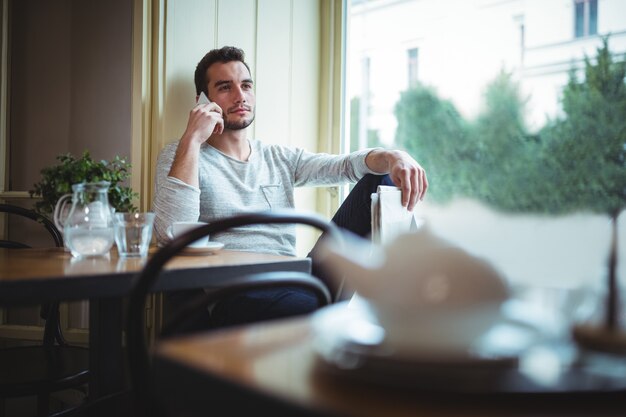 El hombre sentado a la mesa y hablando por teléfono móvil