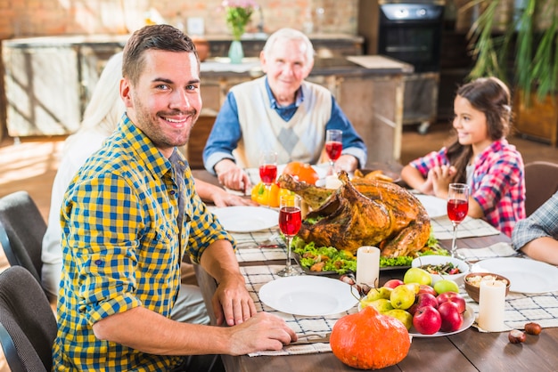 Hombre sentado en la mesa junto a la familia