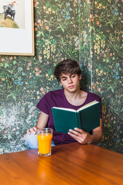 Hombre sentado en la mesa y leyendo el libro